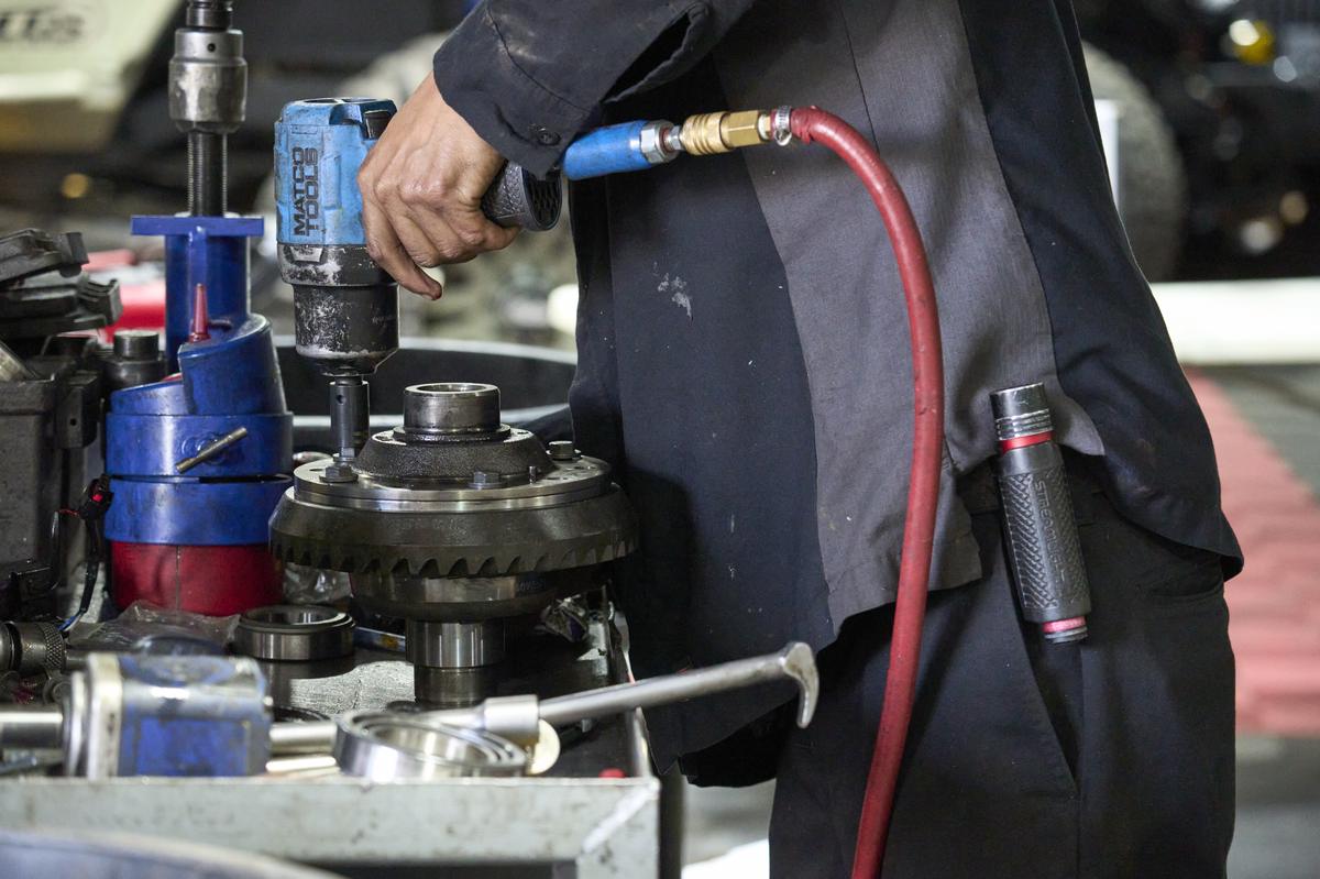 Technician using an impact wrench and bearing press to seat a bearing on a differential carrier and ring gear assembly
